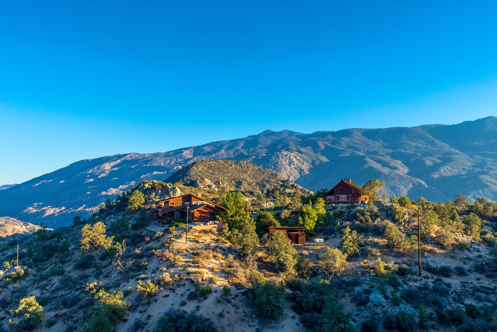Ridge view of the lodge with the San Jacinto Mountains beyond — golden hour at 4,300 feet.